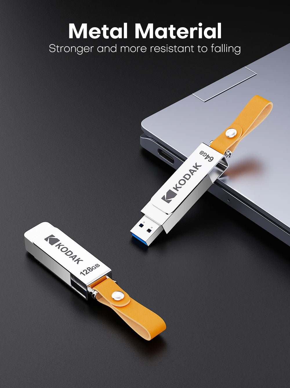 A white Kodak metal USB flash drive with a leather lanyard is shown next to a silver laptop.