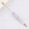 A purple and white DIY beadable pen set with a gold-tipped applicator resting on a light surface.