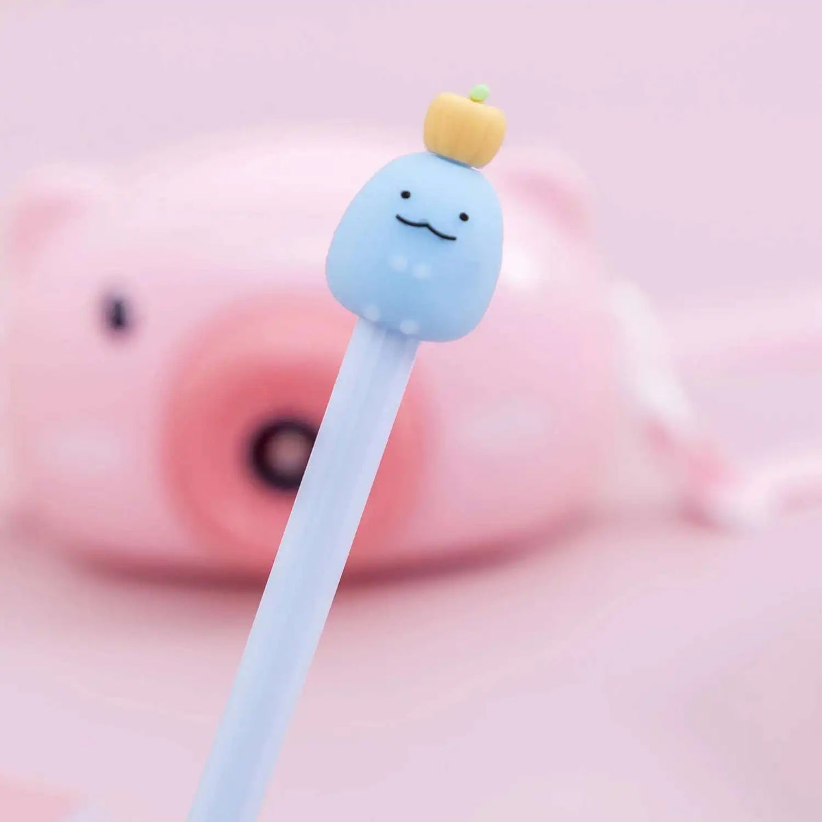 A cute cartoon fruit gel pen with a light blue body and a yellow fruit top is shown against a pink background.