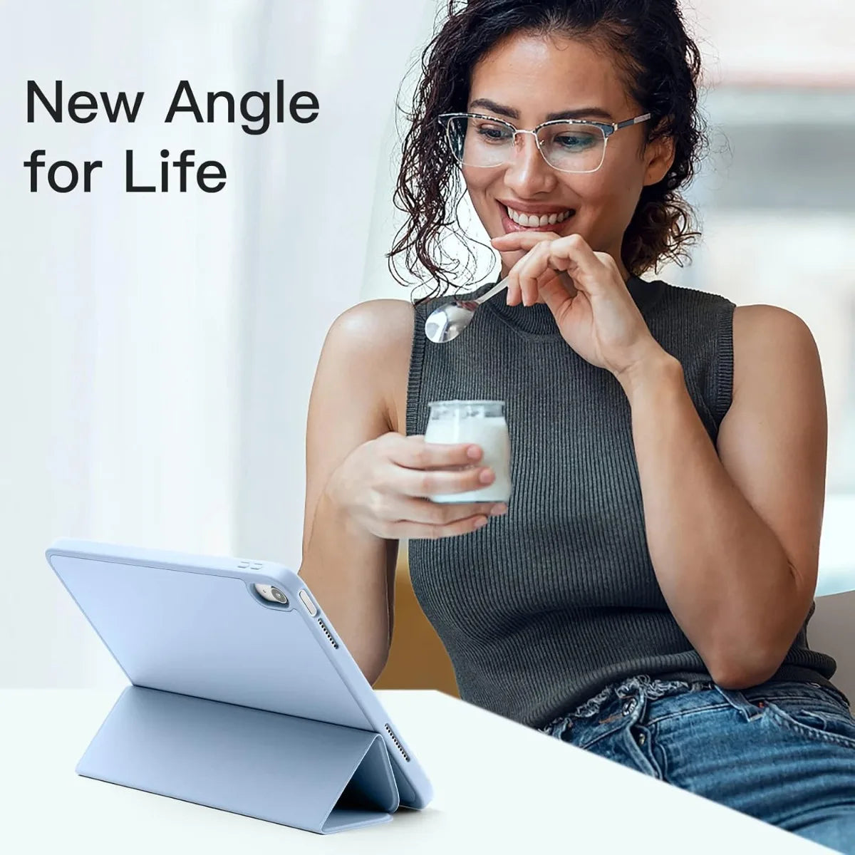 A woman holds a white cup while looking at a tablet, demonstrating a new angle for life.