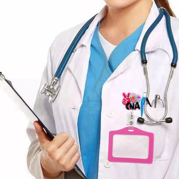 A person wearing a white lab coat and blue scrubs holds a medical stethoscope and a pink badge reel holder.