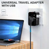 محول سفر أسود متعدد الاستخدامات مع منفذ USB موصول بمأخذ حائط أبيض بجوار حاسوب محمول.