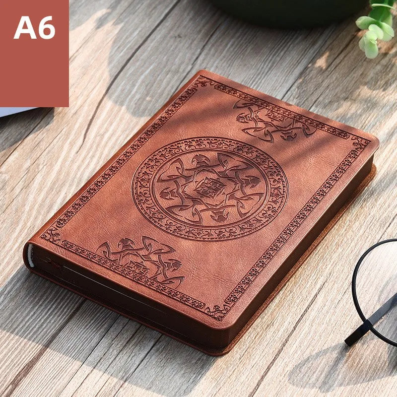 A brown retro PU leather pocket notebook with an embossed circular design resting on a wooden surface.