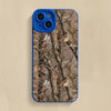Coque de téléphone en silicone bleu avec motif camouflage de forêt, branches et feuilles.