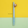 A light blue mechanical pencil with a cute sloth design is shown against a yellow and green background.