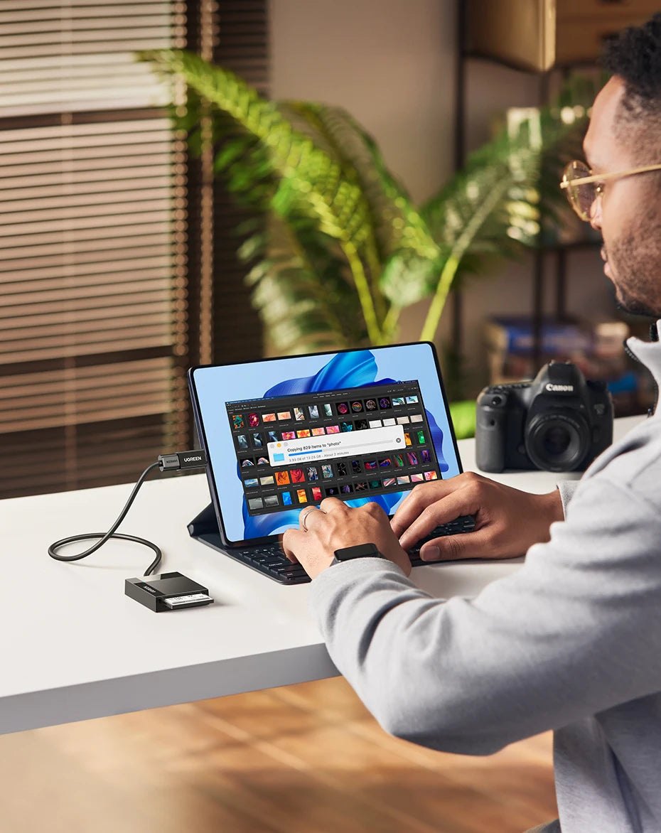 Una persona está usando una laptop para conectar un adaptador multi-tarjeta 4 en 1 con una cámara.