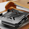 A silver adjustable dual rod tablet and phone stand is shown resting on a brown leather-bound notebook.