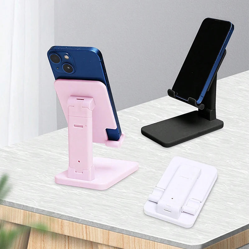 A pink adjustable desktop phone stand holding a blue smartphone and a white tablet.