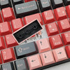 A close-up view of a set of red and pink PBT keycaps for an MX Mechanical keyboard.