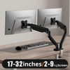 A black ergonomic dual monitor mount is shown adjusting a silver monitor on a wooden desk.