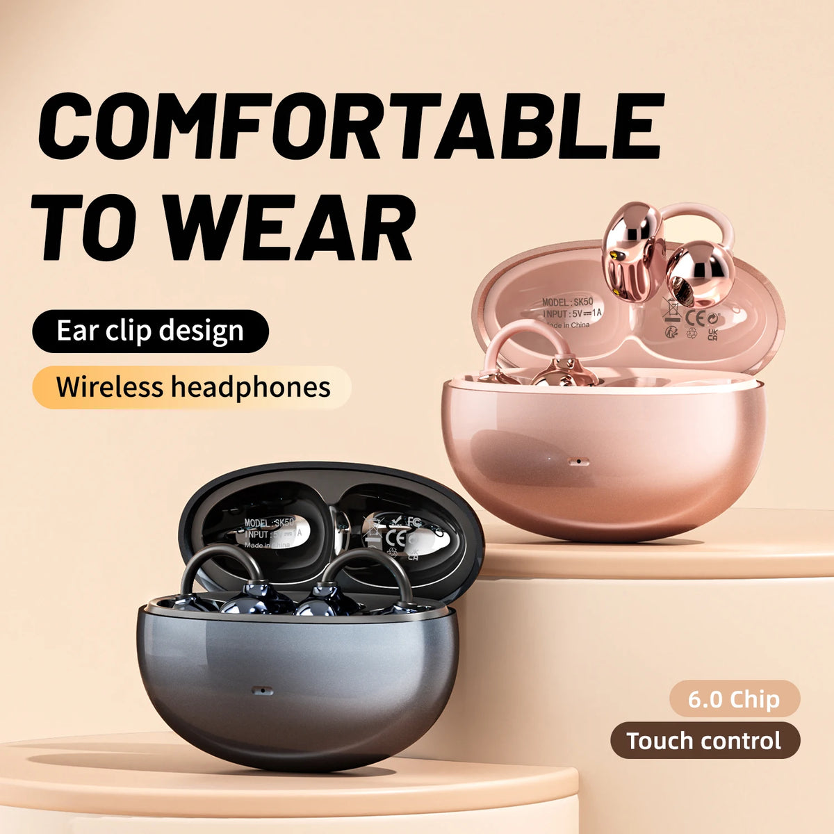 A pink wireless headphone charging case and a dark gray open ear clip design are shown on a light surface.