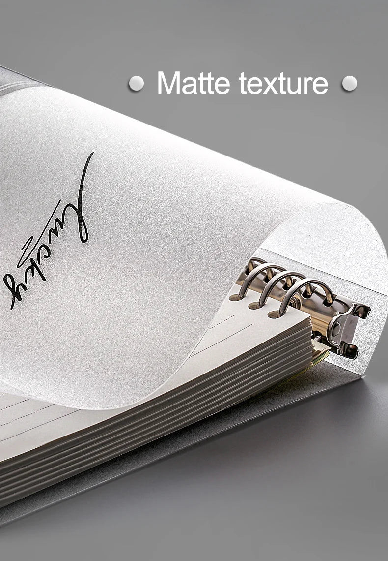 Gros plan d'un carnet à feuilles volantes blanc avec une signature manuscrite sur la couverture, montrant une texture mate.