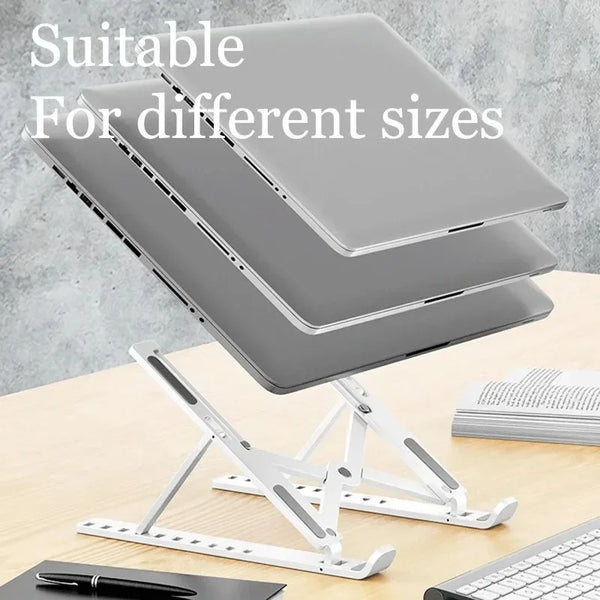 A silver foldable adjustable laptop stand is shown with a laptop resting on it, next to a keyboard and pen.