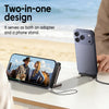A purple smartphone is shown with a black adapter and foldable stand on a white table near the ocean.