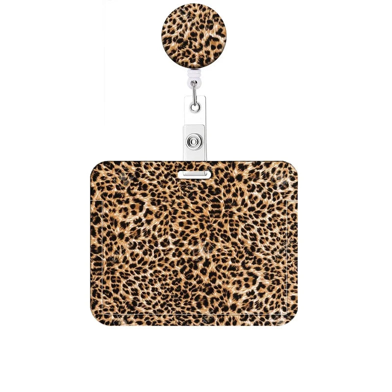 A leopard print retractable badge holder with a round charm attached.