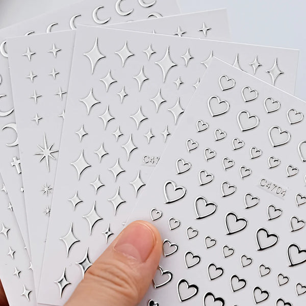 A hand holds a sheet of metallic 3D star nail art stickers, showing various heart and star shapes.
