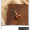 Gold-plated shell pearl beaded bracelet with a red gemstone pendant displayed on dark wood.
