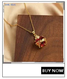Gold-plated shell pearl beaded bracelet with a red gemstone pendant displayed on dark wood.