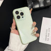 A hand holds a light green iPhone with a clear case and gold nail polish against a black background.