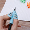 A hand holds a blue silicone pencil grip writing corrector tool above lined paper.