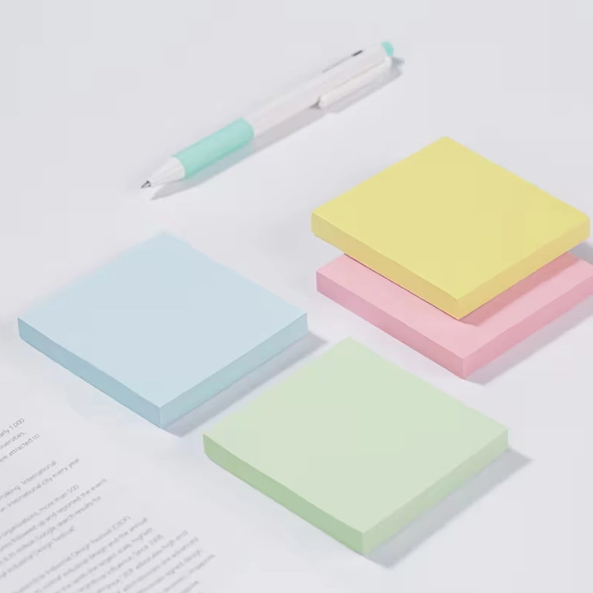 Ein Set bunter quadratischer selbstklebender Notizzettel in Hellblau, Pink und Gelb mit einem weißen Stift.