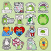 A collection of enamel pins featuring various frogs and humorous text