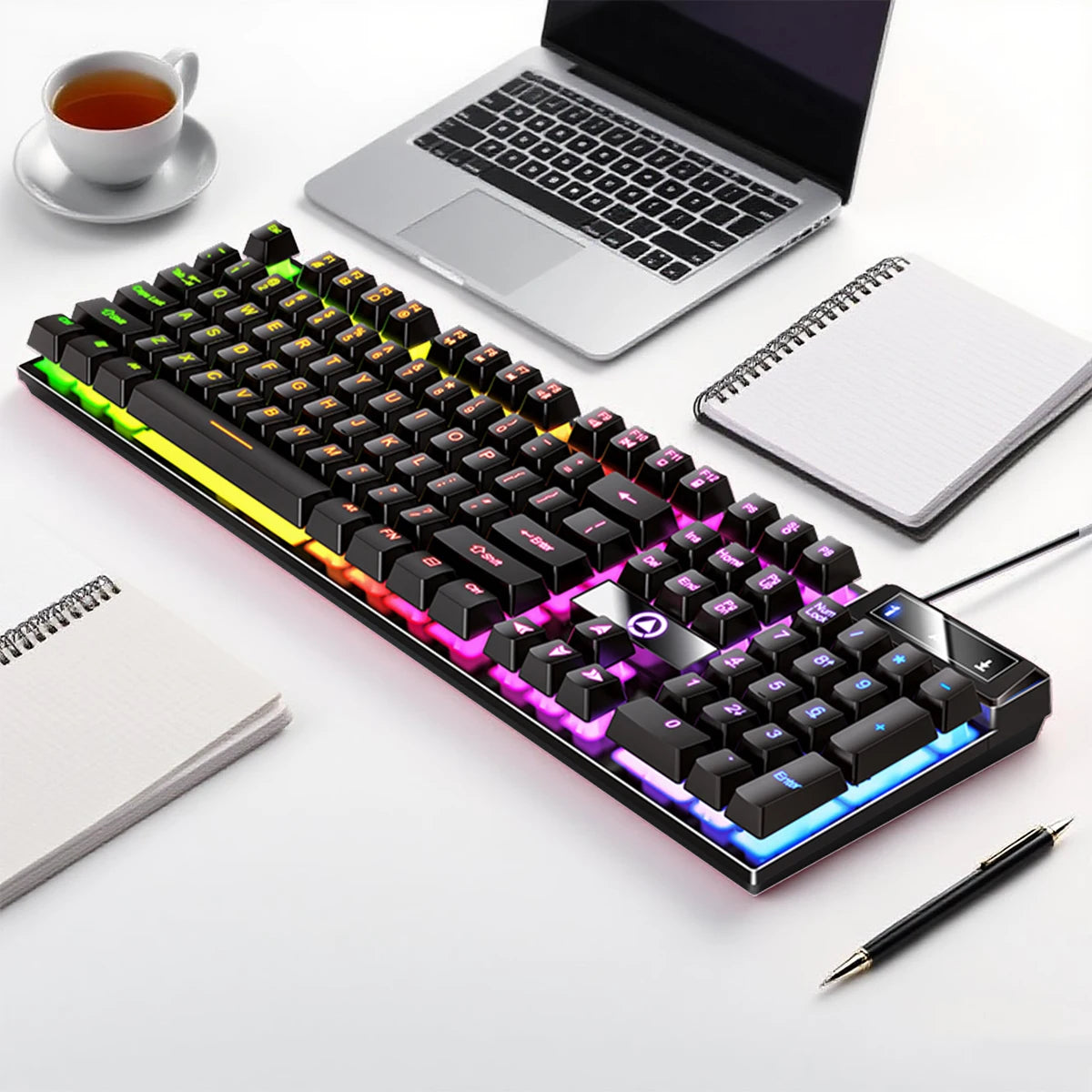 A low profile wired gaming keyboard with a numpad is shown next to a laptop and a cup on a white surface.