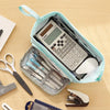 A light blue canvas pencil case is open, showing a Canon calculator and various pens and pencils inside.
