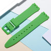 A bright green silicone watch strap is shown next to its replacement tools on a light background.
