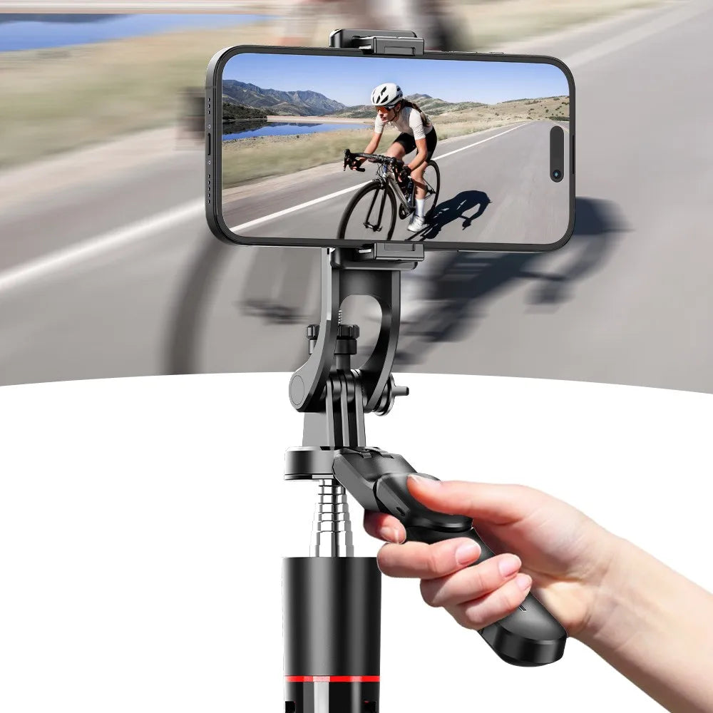 A hand holds a multifunctional selfie stick tripod with a smartphone mounted, capturing an outdoor cycling scene.