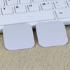 Two white universal magnetic mount plates resting on a light beige surface next to a keyboard.