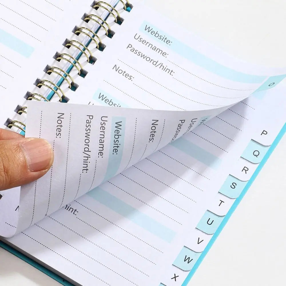 A close-up of an A6 password keeper notebook with lined pages and alphabetical tabs for notes.