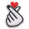 A white charm featuring a red heart and a black hand gesture sign.