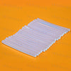A rectangular pack of clear hot melt glue sticks for mini glue guns, laid flat on an orange surface.