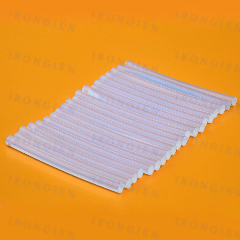 A rectangular pack of clear hot melt glue sticks for mini glue guns, laid flat on an orange surface.