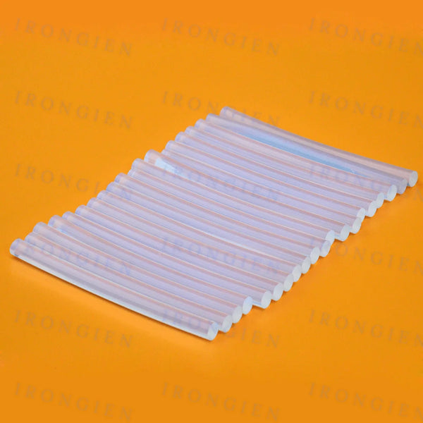 A rectangular pack of clear hot melt glue sticks for mini glue guns, laid flat on an orange surface.