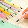 Une main tient un stylo rose écrivant sur du papier ligné, entourée de plusieurs crayons colorés.