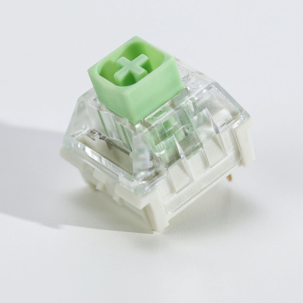 A close-up view of a light green tactile clicky mechanical keyboard switch with a clear plastic housing.