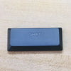 A rectangular blue keycap labeled SHIFT resting on a light beige surface.