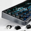 Close-up of black PBT keycaps with blue side lighting on a mechanical keyboard layout.