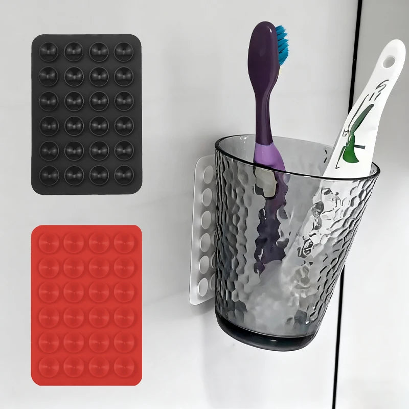 A set of silicone suction cups in black and red, along with a purple silicone tool and a clear glass container.