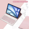 Funda rosa para iPad con teclado Bluetooth desmontable, abierta sobre una superficie de mármol blanco.