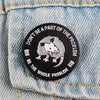 Broche émail noire avec tête de loup menaçant et accents roses sur tissu en denim.
