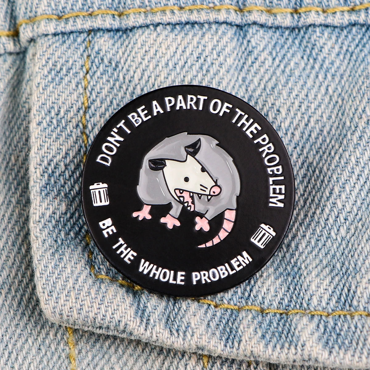 Broche émail noire avec tête de loup menaçant et accents roses sur tissu en denim.