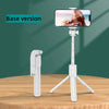 A white selfie stick tripod with a smartphone mounted, featuring a fill light and wireless remote, displayed on a wooden surf