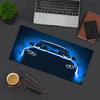 A dark blue car headlight design on a gaming mouse pad with a laptop and writing tools nearby.