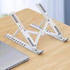 A white portable folding laptop stand is shown resting on a wooden table next to a silver laptop.