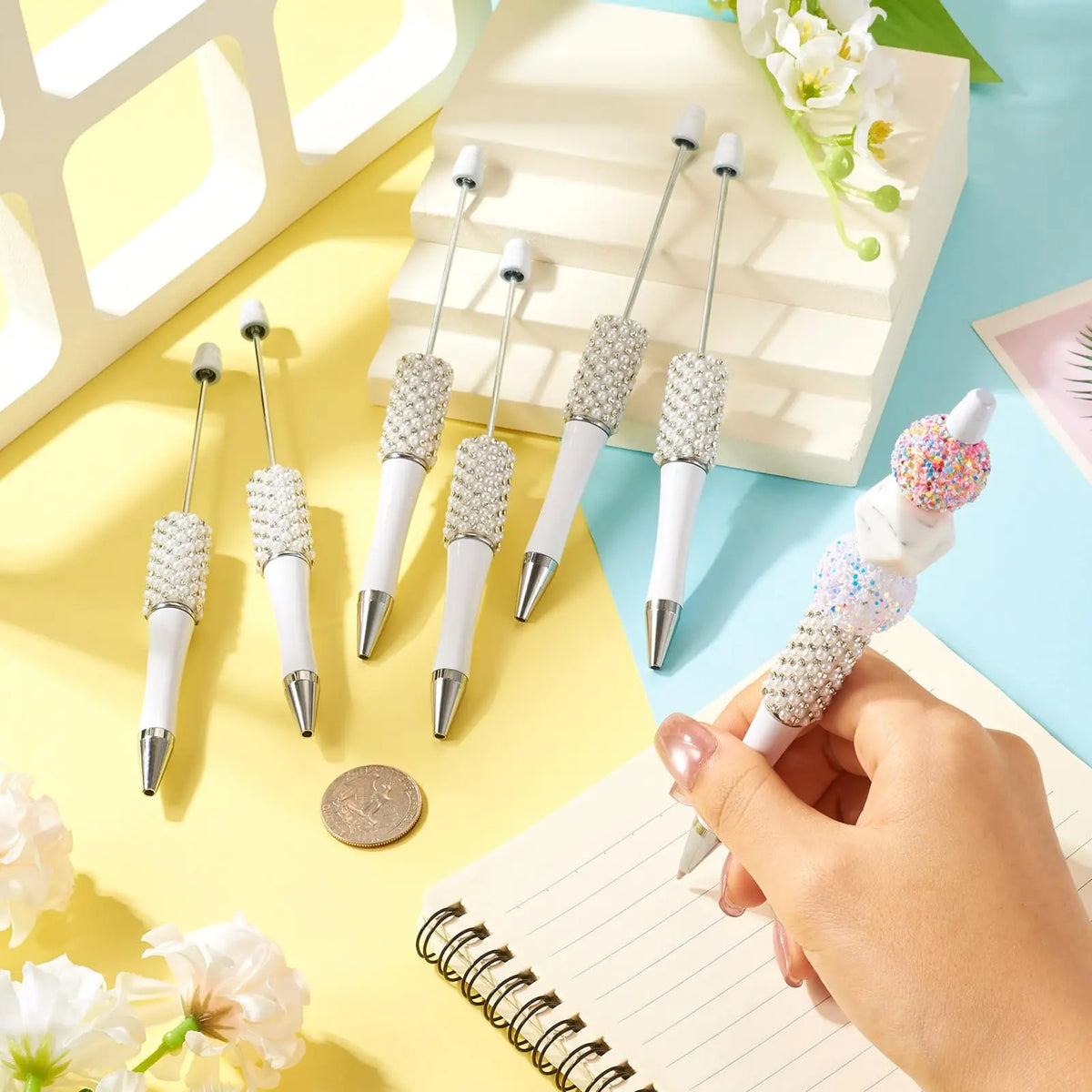 A hand holds a pearl beaded ballpoint pen, showcasing the decorative tips for DIY crafting.