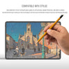 A hand holds a yellow stylus writing on a tablet screen displaying a historical cityscape.