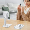 A woman is using a foldable adjustable phone holder stand on a wooden table.